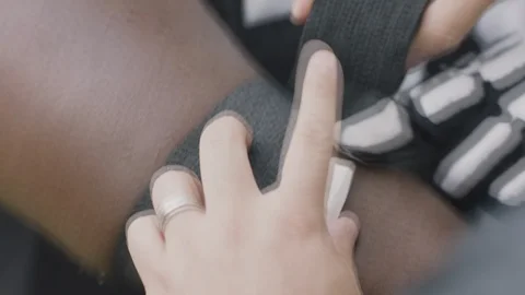 Handheld closeup of man taping wounded players arm Stock Footage 120462162