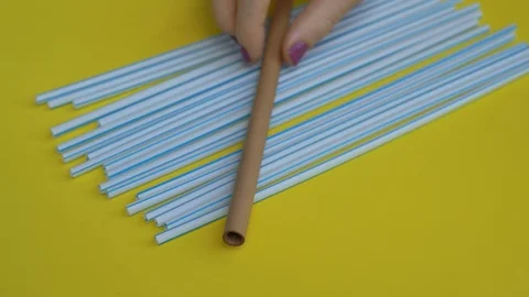 Handheld closeup shot of lots of plastic drinking straws on a colourfull yellow Stock Footage 119291081