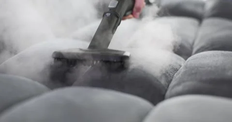 Handheld device emits steam onto sofa with moisture and vapor Stock Footage 314101710