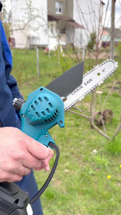 Handheld electric mini chainsaw in use outdoors, compact power tool for pruning  Stock Footage 334787110