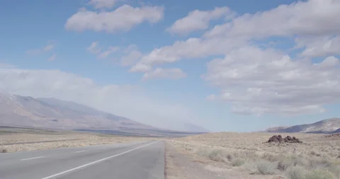 Handheld empty road middle of nowhere snowy mountain range cloudy sky Stock Footage 219331730