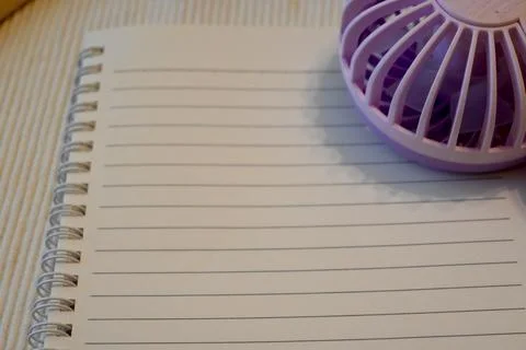 Handheld fan on a lined notebook Photos