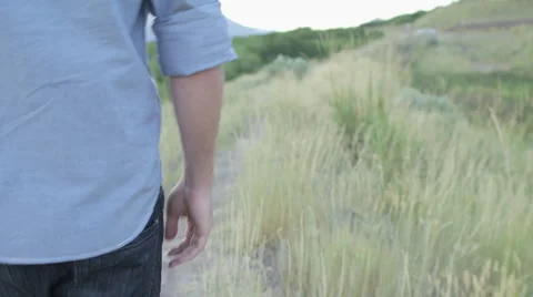 Handheld Follow of Man Walking Down Path Touch Weeds with his Hand 動画素材 68723647