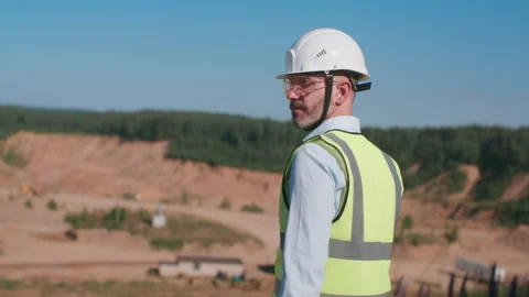 Handheld following handsome sand quarry worker engineer in safety wear hardhat Stock Footage 156458984