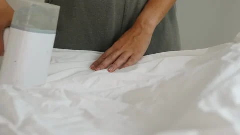 Handheld garment steamer smoothing white fabric, domestic home use 動画素材 332722775