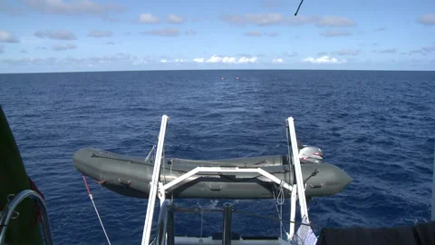 Handheld long shot of two men kayaking behind a boat Stock Footage 310539797