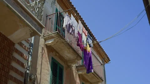Handheld Low-Angle Pan of City Balcony with Laundry Swaying Stock Footage 315814631