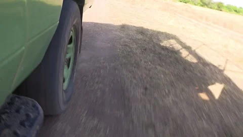 Handheld low-angle POV beside the rear tire of a safari vehicle rolling along a Stock Footage 337246433