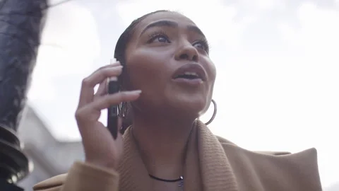 Handheld low angle shot of young attractive female talking on her phone out in t Stock Footage 252437240