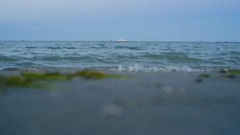 Handheld Low-Angle Still of Shoreline with Illuminated Ship at Sunset Stock Footage 315758705