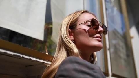 Handheld low angle view of beautiful woman with sunglasses standing and posing Stock Footage 120420267