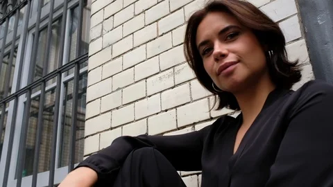 Handheld low angle view of beautiful woman sitting and posing Stock Footage 120421941