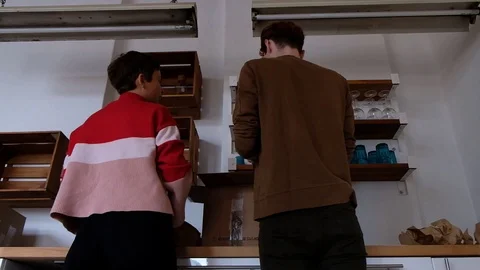 Handheld low angle view of friends unpacking box at home Stock Footage 120425110