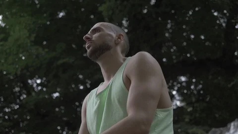 Handheld low angle view of man sitting on wall in park Stock-Footage 114843751