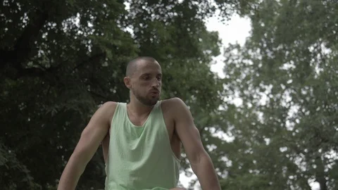 Handheld low angle view of man sitting on wall in park Vídeo Stock 114843753