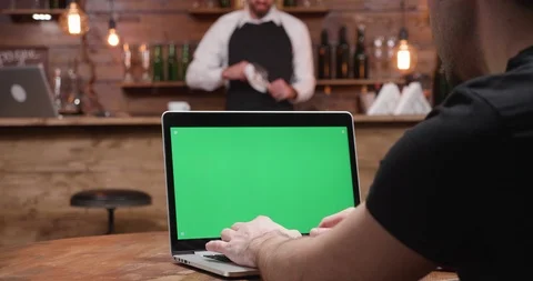 Handheld: Man types fast on a modern laptop with green screen Stock Footage 104495271