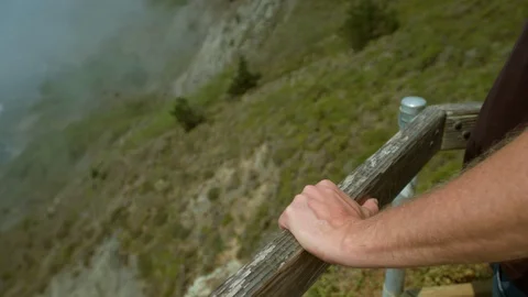 Handheld, a man's hands grip the railing at an outlook, the Panoramic Highway Stock Footage 94132028