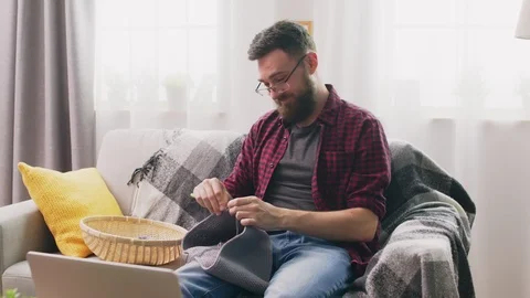 Handheld medium shot of comic man knitting at home Video stock 107354989