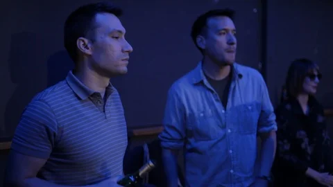 Handheld medium shot of two men chat and drink against wall in nightclub Video stock 114847905