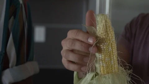 Handheld mid section of man removing corn husk while standing by friend Stock Footage 114878659