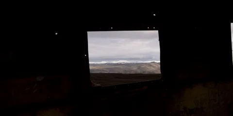 Handheld mountains framed through window of crashed plane at Sólheimasandur Stock Footage 122910003