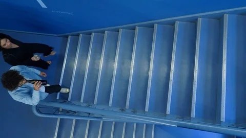 Handheld overhead view of young man and woman walking up stairs with drinks Vídeo Stock 114871957