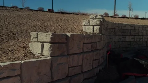Handheld Pan Along Stone Retaining Wall at Construction Site Stock Footage 330919311
