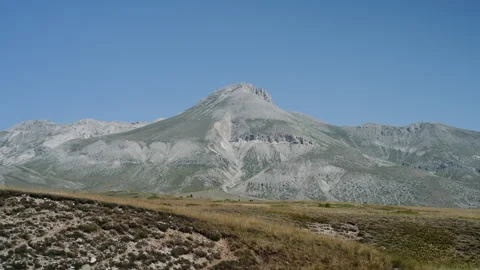 Handheld Pan of Grassy Mountain Valley with White Rocky Peaks Stock Footage 315742285