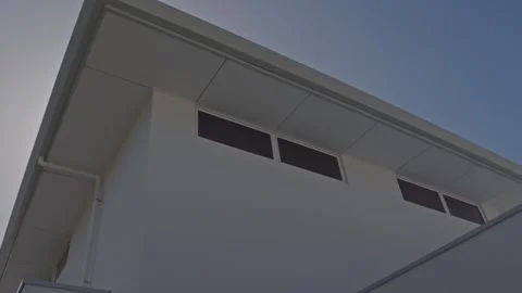 Handheld Pan of Luxury Home's Upper Windows with Sunlight Against Blue Sky Stock Footage 304092241