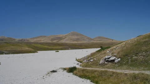 Handheld Pan of Mountain Valley with Arid Land and Rocky Peaks Stock Footage 315829506