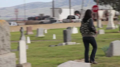Handheld pan over to person walking thru graveyard Stock Footage 155326760