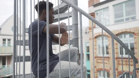 Handheld panning shot of young man practicing dance while sitting Stock Footage 120424009