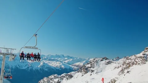 Handheld people in ski lift blue bright sky and beautiful white snowy alps Stock Footage