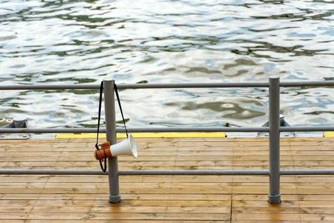 Handheld portable megaphone loudspeaker hanging on the railing of the river p Stock Photos