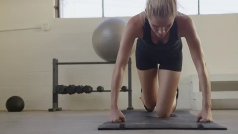 Handheld portrait of female athlete doing push-ups on exercise mat at gym Stock Footage