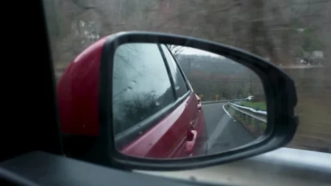 Handheld POV Of Red Car Side Mirror Driving On Winding Road By Lake Stock Footage 332065099