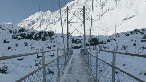 Handheld POV walk across the first suspension bridge on the snow-covered Hooker Stock Footage 313342308