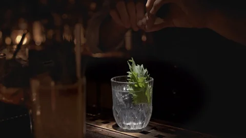 Handheld real time close up shot of a bartender preparing a cocktail at a bar in 動画素材 128655836