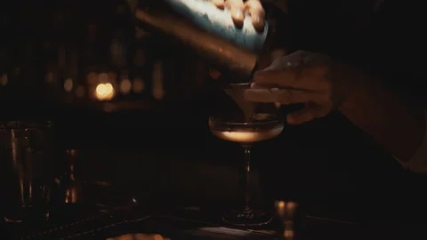 Handheld real time close up shot of a bartender pouring a cocktail into a glass 스톡 동영상 129493270