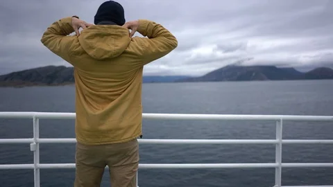Handheld rear view of a man looking at the scenic seacoast Stock Footage 114883244