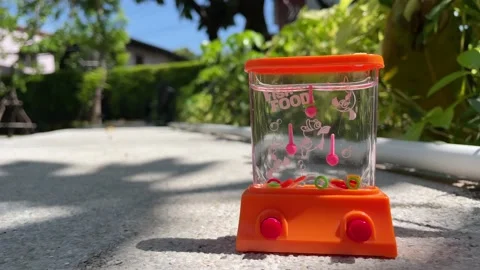Handheld retro water game ring arcade garden blue sky sunny day. Nostalgic toy Stock Footage 230095874