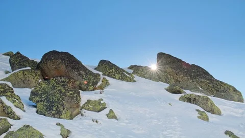 Handheld rocks with snow on a mountain with the sun and a lens flare Stock Footage 71121687