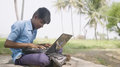 Handheld of school kid busy using laptop under tree outside the school near Stock Footage 187940926