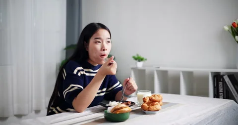 Handheld selective focus shot, Happy Asian woman eating rice at dining tabl.. Stockbeeldmateriaal 287160110