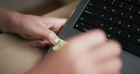 Handheld selective focus shot, A woman's hand sticks a note with text on a .. Видео 313868289
