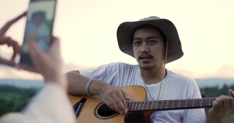 Handheld, Selective focus Young man play guitar and sing a song, pretty woman Stock-Footage 219599639