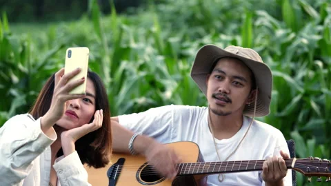 Handheld, Selective focus Young man play guitar and sing a song, pretty woman Stockbeeldmateriaal 219613102