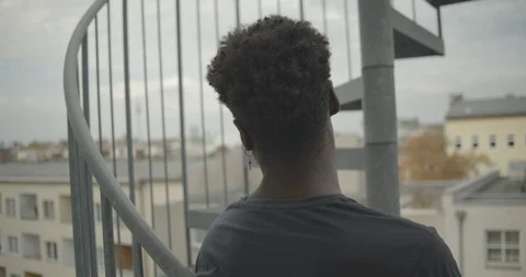 Handheld shot and rear view of man standing at fire escape against sky Stock Footage 120431453