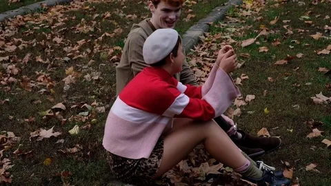 Handheld shot and side view of friends sitting and talking in the park Stock Footage 120429650