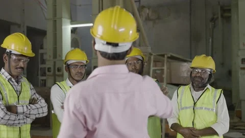 Handheld shot of back view of supervisor advising or briefing work to employees Stock Footage 172251048